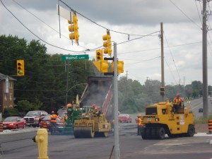 Paving and rolling operation underway at a signalized intersection
